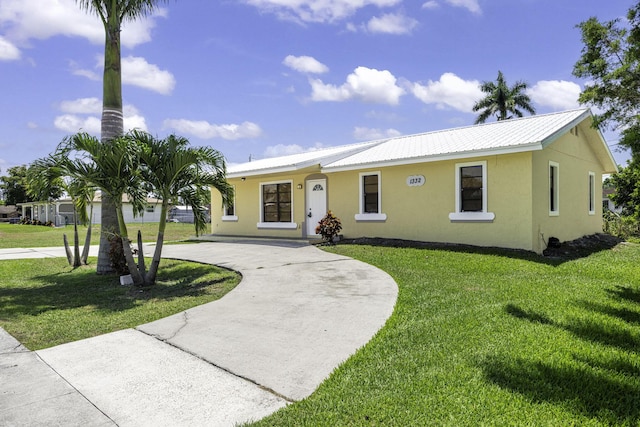 1332 SW G, Belle Glade, FL 33430 - ranch-style home featuring stucco siding, curved driveway, a front lawn, and metal roof