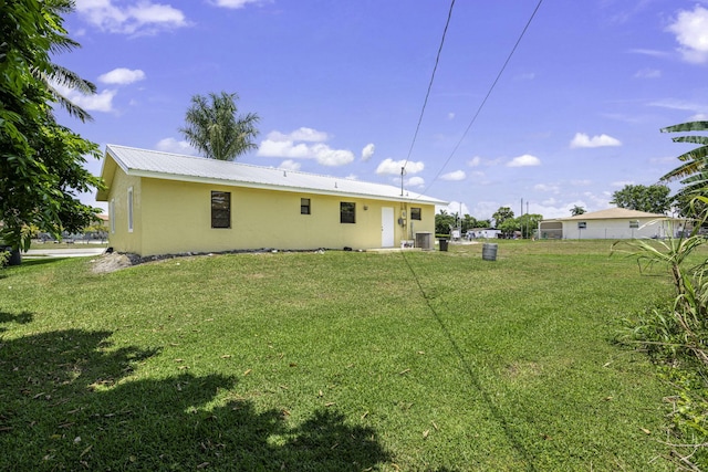1332 SW G, Belle Glade, FL 33430 - rear view of property featuring stucco siding, a yard, central AC, and metal roof