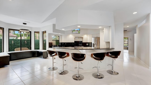 7245 Montrico Dr, Boca Raton, FL 33433 - kitchen featuring stainless steel fridge with ice dispenser, plenty of natural light, a breakfast bar, vaulted ceiling, and recessed lighting