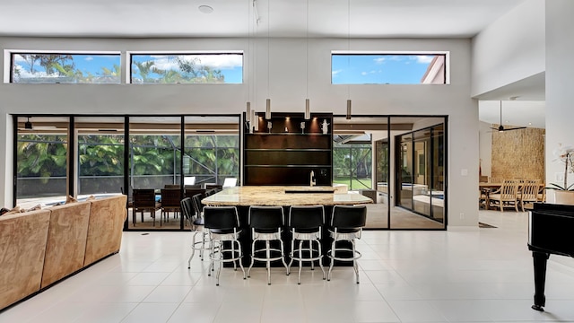 7245 Montrico Dr, Boca Raton, FL 33433 - kitchen with a towering ceiling, light stone counters, a kitchen bar, modern cabinets, and a kitchen island