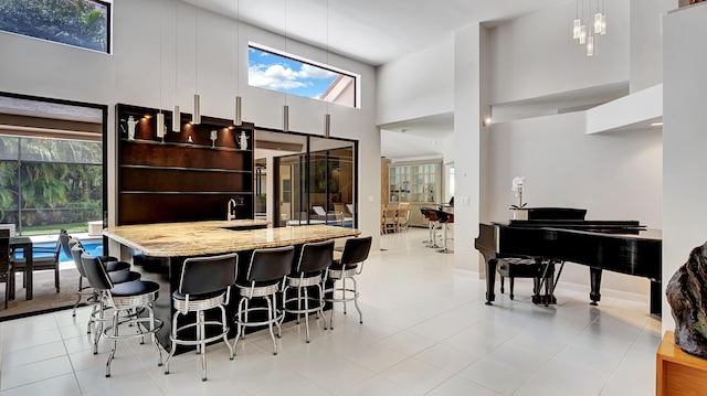 7245 Montrico Dr, Boca Raton, FL 33433 - kitchen featuring light stone counters, decorative light fixtures, modern cabinets, a kitchen breakfast bar, and a towering ceiling