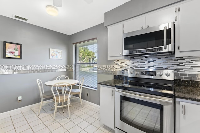 6166 Brandon St, Palm Beach Gardens, FL 33418 - kitchen featuring appliances with stainless steel finishes, light tile patterned flooring, white cabinets, and decorative backsplash