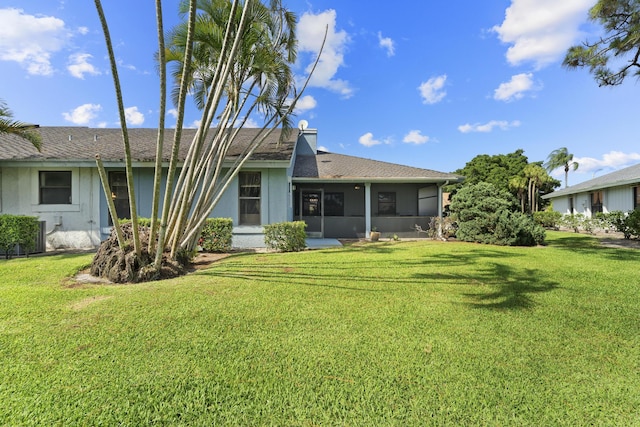 6166 Brandon St, Palm Beach Gardens, FL 33418 - rear view of house featuring a lawn, a sunroom, and a shingled roof