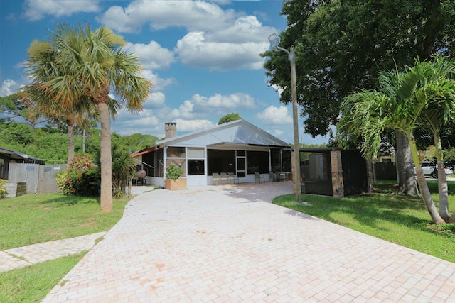 4811 Seagrape Dr, Fort Pierce, FL 34982 - view of front of house with a sunroom, a chimney, and decorative driveway