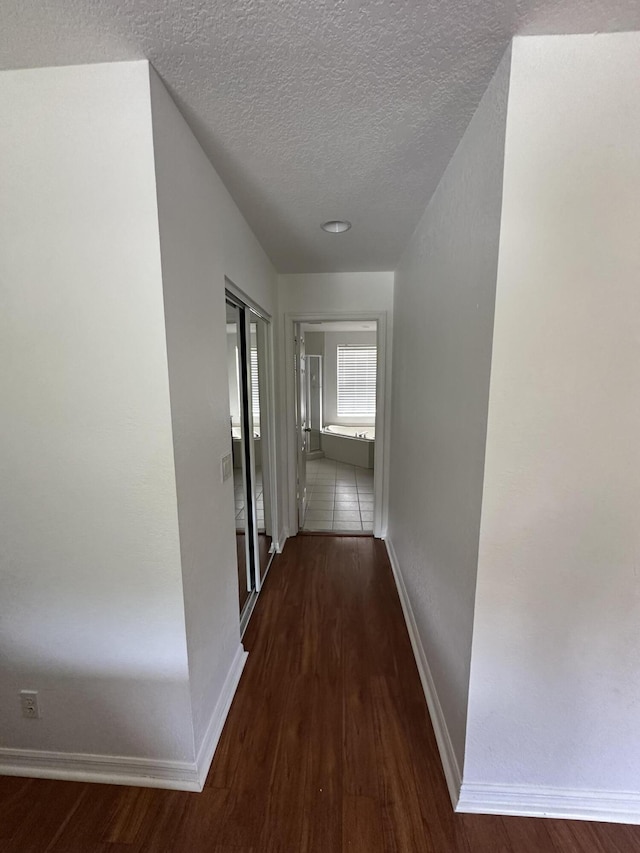 4097 Bluff Harbor Way, Wellington, FL 33449 - hallway featuring wood finished floors, a textured ceiling, and baseboards