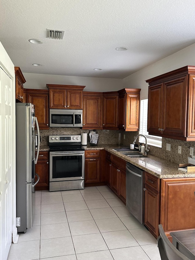 4097 Bluff Harbor Way, Wellington, FL 33449 - kitchen featuring appliances with stainless steel finishes, tasteful backsplash, a sink, stone countertops, and light tile patterned floors