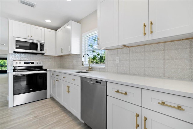 13921 Royal Palm Ct Unit D, Delray Beach, FL 33484 - kitchen featuring appliances with stainless steel finishes, a sink, white cabinets, light wood finished floors, and backsplash