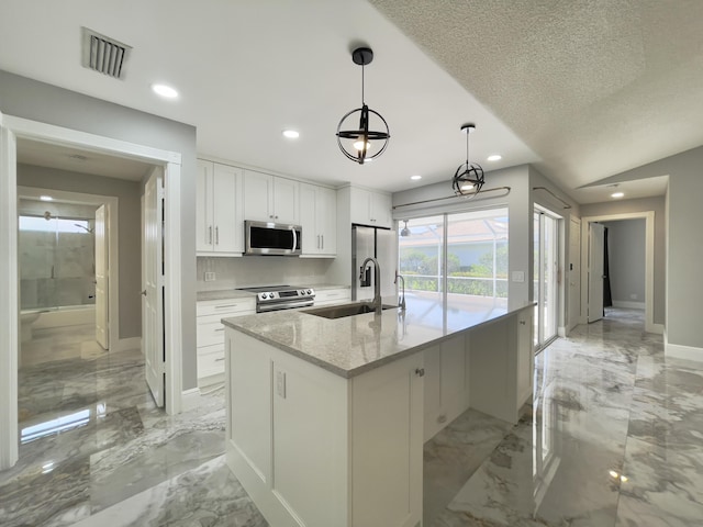 6503 Geminata Oak Ct, Palm Beach Gardens, FL 33410 - kitchen with stainless steel appliances, light marble finish floors, a sink, white cabinets, and a kitchen island with sink