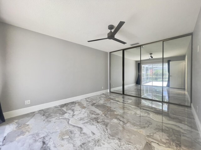 6503 Geminata Oak Ct, Palm Beach Gardens, FL 33410 - unfurnished bedroom featuring marble finish flooring, baseboards, ceiling fan, and a textured ceiling