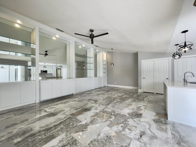 6503 Geminata Oak Ct, Palm Beach Gardens, FL 33410 - unfurnished living room with a ceiling fan, a textured ceiling, baseboards, marble finish flooring, and a sink