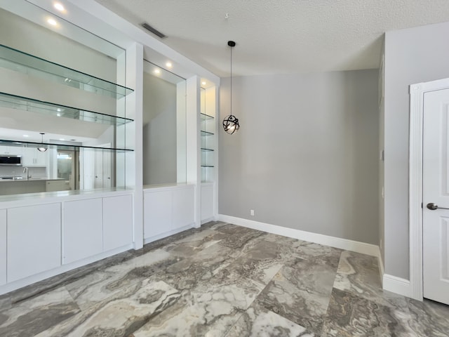 6503 Geminata Oak Ct, Palm Beach Gardens, FL 33410 - empty room featuring baseboards, marble finish floors, a textured ceiling, and a sink