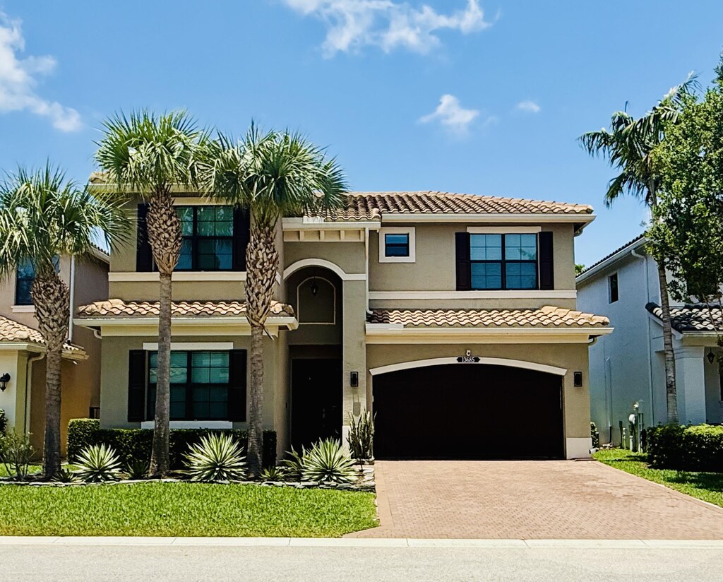 13685 Moss Agate Ave, Delray Beach, FL 33446 - mediterranean / spanish-style house featuring a tiled roof, decorative driveway, stucco siding, and an attached garage