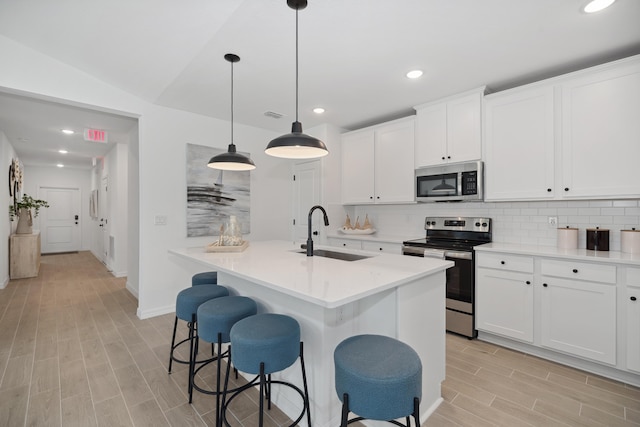201 Ocarina St SW Unit 78, Palm Bay, FL 32908 - kitchen with appliances with stainless steel finishes, a sink, light wood finished floors, backsplash, and a kitchen island with sink