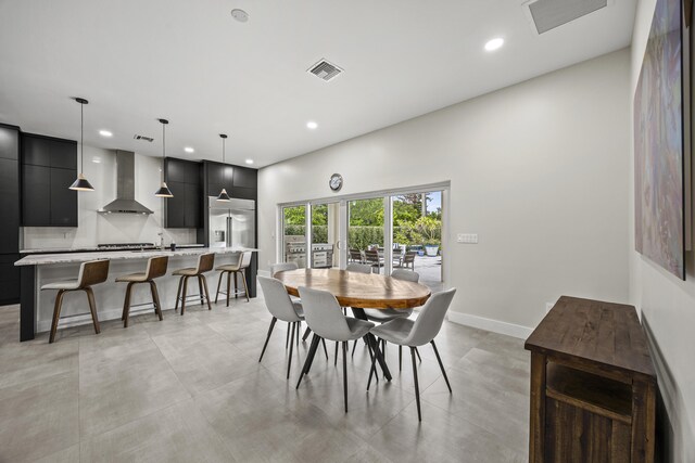 7802 Martin Ave, West Palm Beach, FL 33405 - kitchen with dark cabinetry, wall chimney range hood, high end refrigerator, modern cabinets, and a breakfast bar area