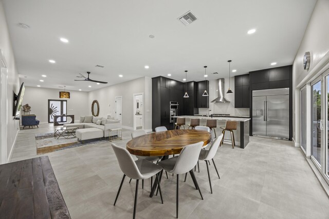 7802 Martin Ave, West Palm Beach, FL 33405 - kitchen featuring appliances with stainless steel finishes, wall chimney range hood, dark cabinetry, a sink, and a center island with sink