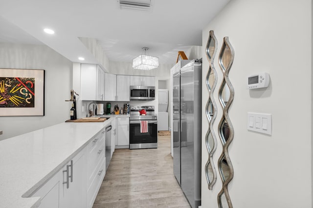 6699 NW 2nd Ave Unit 109, Boca Raton, FL 33487 - kitchen with appliances with stainless steel finishes, white cabinets, light countertops, a sink, and light wood finished floors
