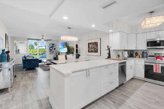 6699 NW 2nd Ave Unit 109, Boca Raton, FL 33487 - kitchen featuring appliances with stainless steel finishes, a peninsula, a chandelier, light wood-style floors, and recessed lighting