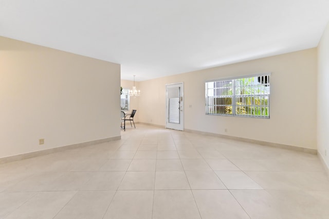 7 Normandy Unit A, Delray Beach, FL 33484 - spare room featuring a chandelier, healthy amount of natural light, light tile patterned flooring, and baseboards