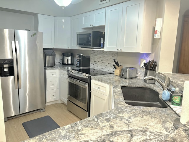 700 Scotia Dr Unit 202, Hypoluxo, FL 33462 - kitchen with stainless steel appliances, a sink, light wood-type flooring, light stone counters, and white cabinets