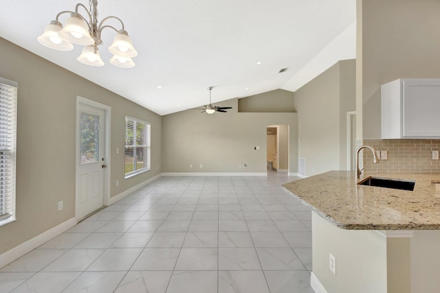 1897 SW Lofgren Ave, Port Saint Lucie, FL 34953 - kitchen with a sink, vaulted ceiling, a ceiling fan, a chandelier, and white cabinets