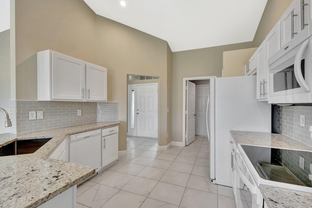 1897 SW Lofgren Ave, Port Saint Lucie, FL 34953 - kitchen with white appliances, a sink, light stone counters, decorative backsplash, and white cabinetry