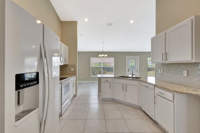 1897 SW Lofgren Ave, Port Saint Lucie, FL 34953 - kitchen with white appliances, a sink, a peninsula, backsplash, and white cabinetry