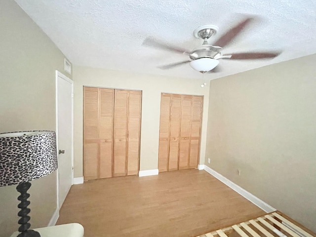 829 Camino Rd Unit 206-C, Delray Beach, FL 33445 - bedroom with two closets, light wood-style flooring, a textured ceiling, baseboards, and a ceiling fan