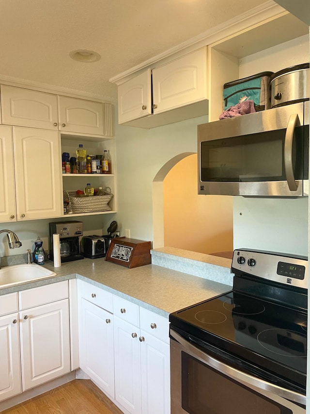 829 Camino Rd Unit 206-C, Delray Beach, FL 33445 - kitchen featuring stainless steel appliances, a sink, arched walkways, light countertops, and white cabinetry