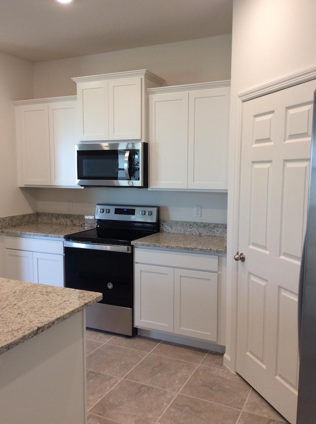10552 SW Toren Way, Port Saint Lucie, FL 34987 - kitchen with appliances with stainless steel finishes, white cabinetry, light stone counters, and light tile patterned flooring