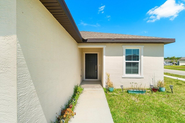 5174 Armina Pl, Fort Pierce, FL 34951 - view of exterior entry featuring stucco siding, a yard, and a shingled roof