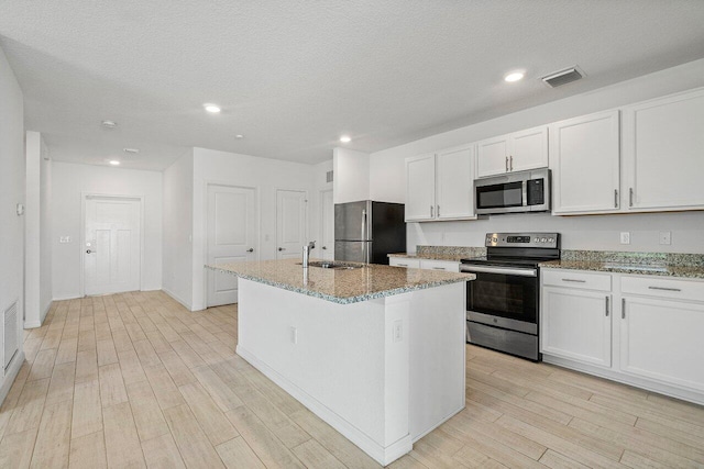 5174 Armina Pl, Fort Pierce, FL 34951 - kitchen with stainless steel appliances, a sink, light wood-style floors, a center island with sink, and stone counters