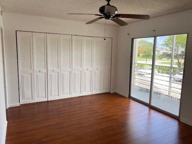 317 Dorset H Unit 317, Boca Raton, FL 33434 - unfurnished bedroom featuring access to exterior, wood finished floors, a textured ceiling, ceiling fan, and baseboards