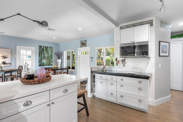 164 Bryn Mawr Dr, Lake Worth Beach, FL 33460 - kitchen featuring stainless steel microwave, tasteful backsplash, dark wood finished floors, white cabinetry, and recessed lighting