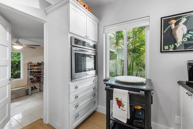 164 Bryn Mawr Dr, Lake Worth Beach, FL 33460 - kitchen with healthy amount of natural light, white cabinets, oven, and a ceiling fan