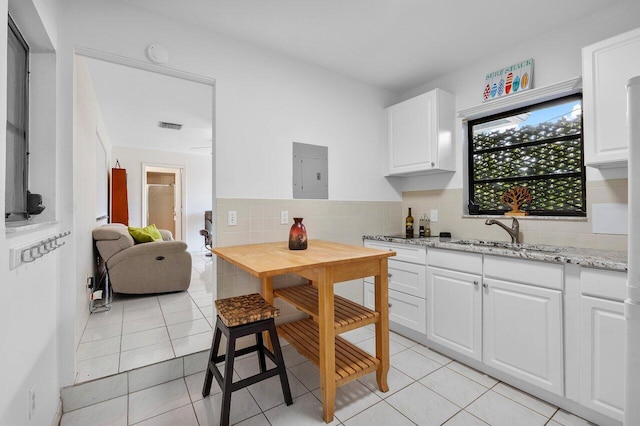 164 Bryn Mawr Dr, Lake Worth Beach, FL 33460 - kitchen featuring electric panel, white cabinetry, backsplash, light stone counters, and light tile patterned flooring