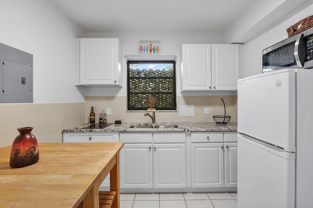 164 Bryn Mawr Dr, Lake Worth Beach, FL 33460 - kitchen featuring freestanding refrigerator, electric panel, white cabinetry, light tile patterned floors, and stainless steel microwave