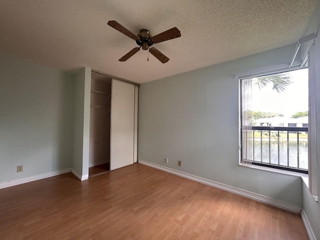 3400 NW 47th Ave Unit 3161, Coconut Creek, FL 33063 - unfurnished bedroom with wood finished floors, a closet, baseboards, a textured ceiling, and a ceiling fan