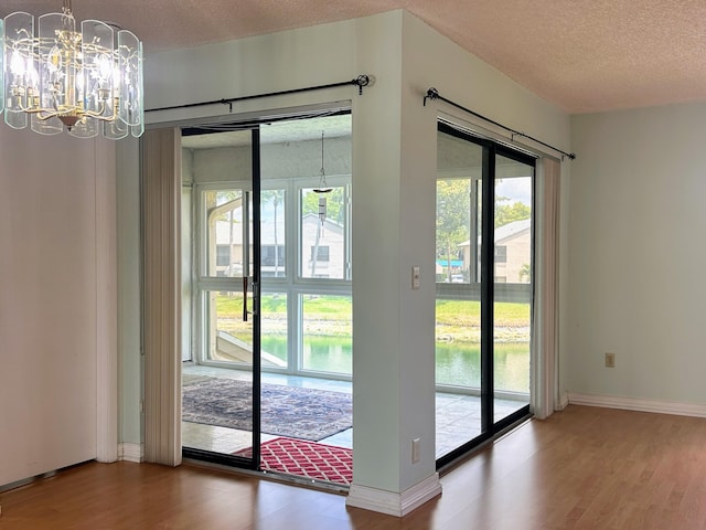 3400 NW 47th Ave Unit 3161, Coconut Creek, FL 33063 - doorway featuring wood finished floors, a textured ceiling, baseboards, a chandelier, and a water view