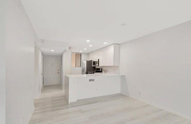 4345 Trevi Ct Unit 203, Lake Worth, FL 33467 - kitchen featuring stainless steel appliances, light countertops, white cabinetry, a peninsula, and light wood-style floors