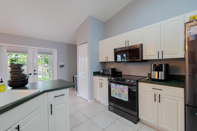 143 Monterey Way, Royal Palm Beach, FL 33411 - kitchen featuring appliances with stainless steel finishes, vaulted ceiling, dark countertops, light tile patterned floors, and white cabinets