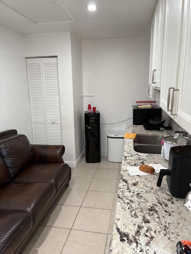 305 E 6th St, Lehigh Acres, FL 33972 - kitchen featuring a sink, light tile patterned floors, white cabinetry, light stone countertops, and baseboards