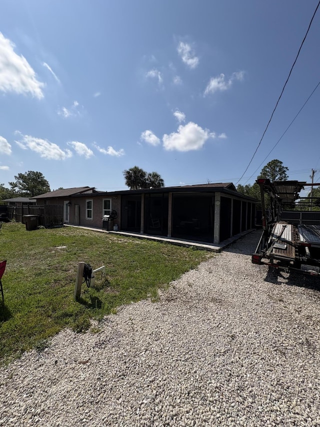 305 E 6th St, Lehigh Acres, FL 33972 - rear view of house with a sunroom and a lawn