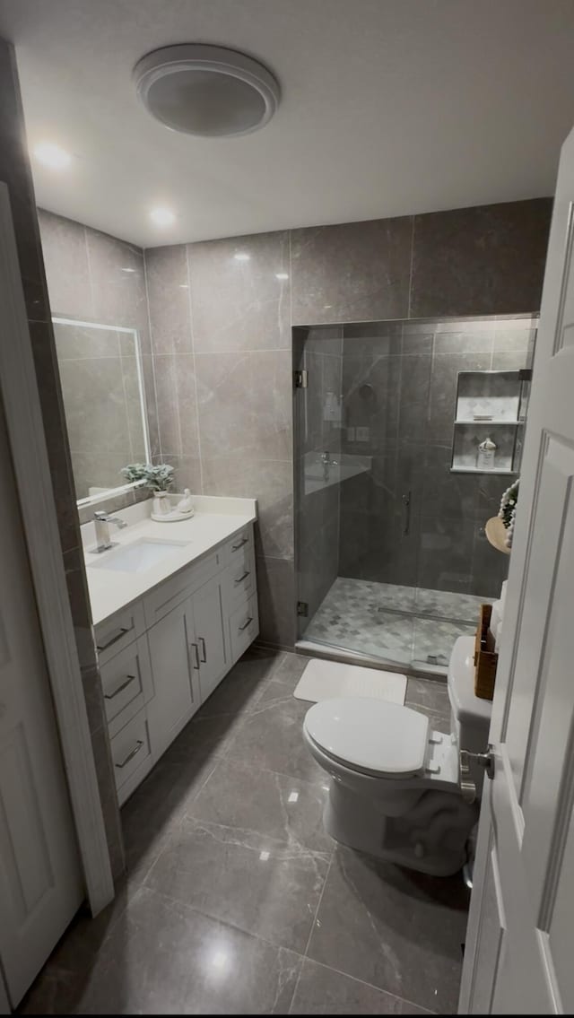 305 E 6th St, Lehigh Acres, FL 33972 - full bathroom with toilet, a shower stall, vanity, marble tiled flooring, and tile walls