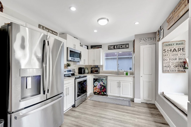 22360 Overture Cir, Boca Raton, FL 33428 - kitchen with stainless steel appliances, white cabinetry, light countertops, a sink, and light wood finished floors