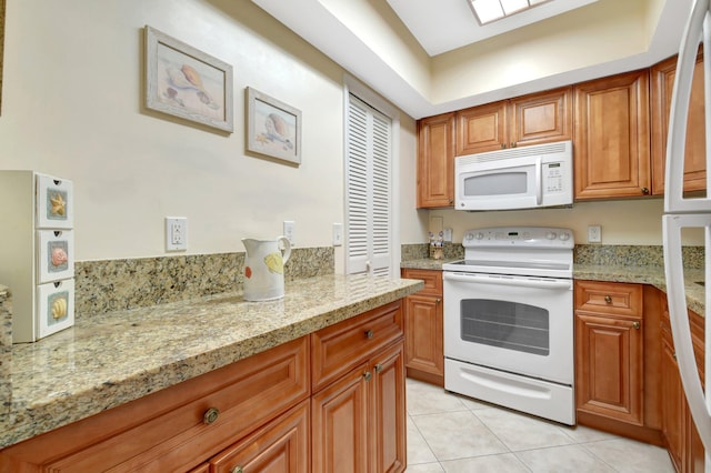 5505 N Ocean Blvd Unit 13-105, Ocean Ridge, FL 33435 - kitchen with white appliances, light tile patterned floors, brown cabinets, and light stone counters