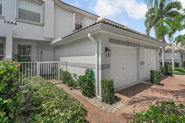 7886 Laina Ln Unit 2, Boynton Beach, FL 33437 - view of side of home featuring stucco siding, a garage, and a tiled roof