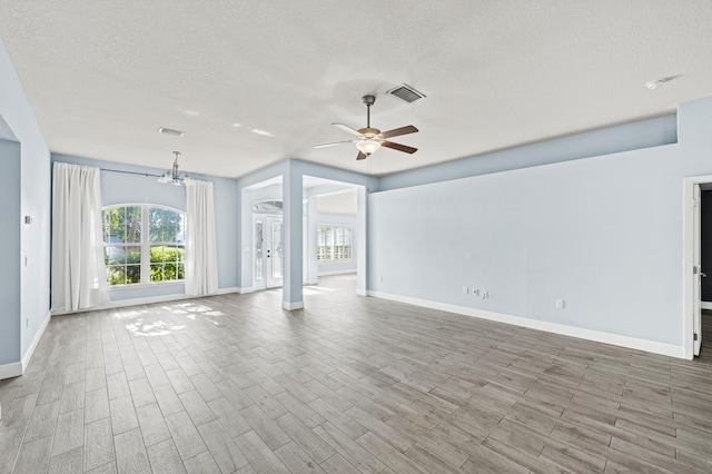 4672 SW Wade Dr, Port Saint Lucie, FL 34953 - unfurnished living room with plenty of natural light, baseboards, ceiling fan, and a textured ceiling