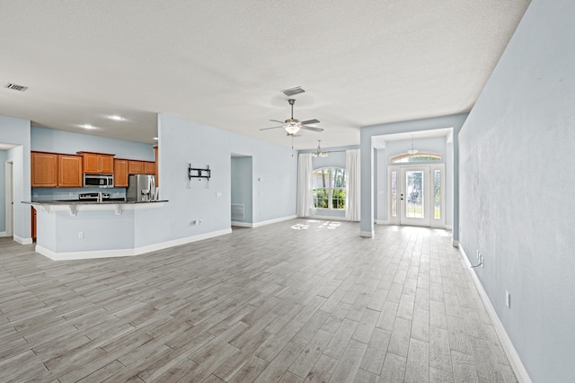 4672 SW Wade Dr, Port Saint Lucie, FL 34953 - unfurnished living room with baseboards, light wood-style floors, ceiling fan, and a textured ceiling