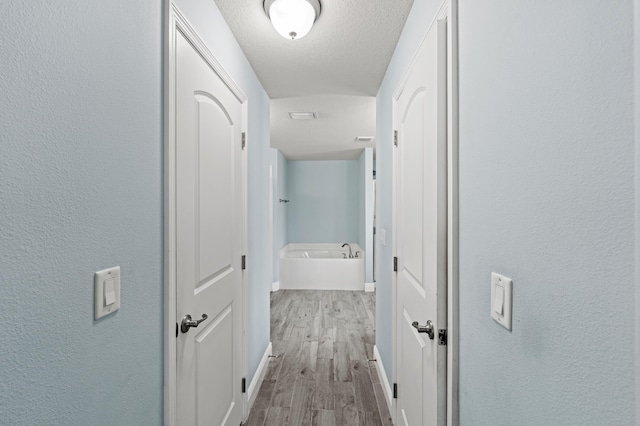 4672 SW Wade Dr, Port Saint Lucie, FL 34953 - corridor with wood finished floors, a textured ceiling, baseboards, and a textured wall