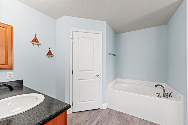 4672 SW Wade Dr, Port Saint Lucie, FL 34953 - full bathroom featuring a bath, wood finished floors, vanity, and a textured ceiling